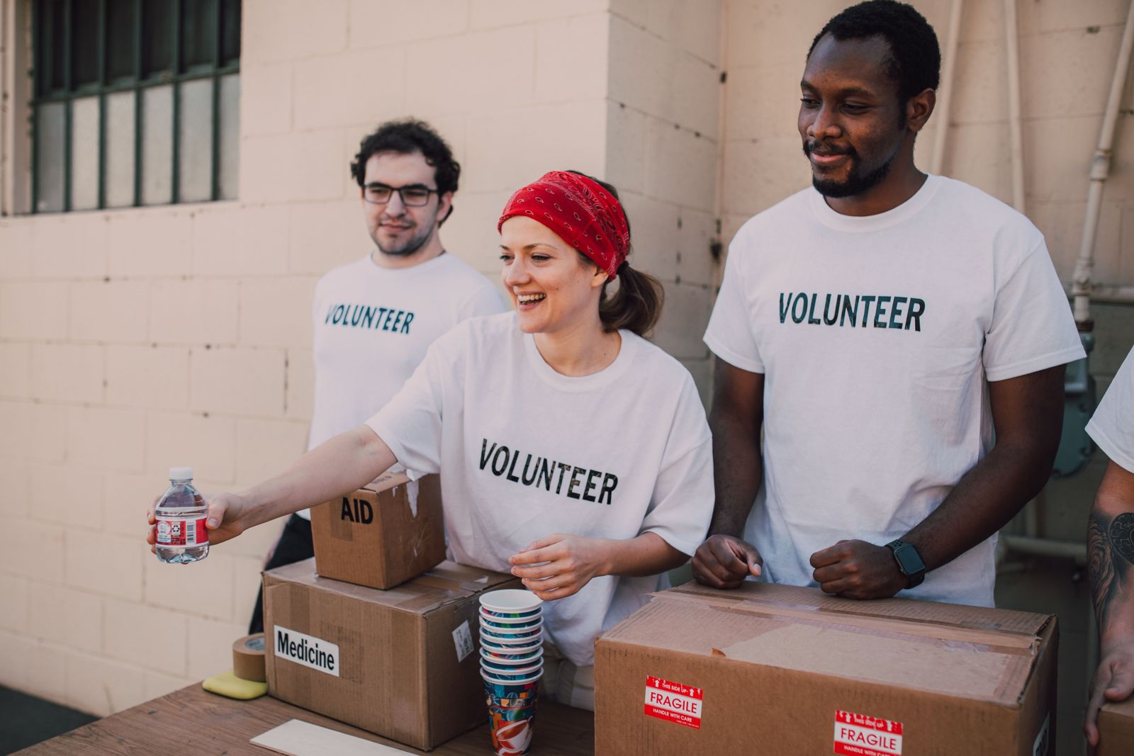 Smiling volunteers handing out water and supplies from donation boxes
